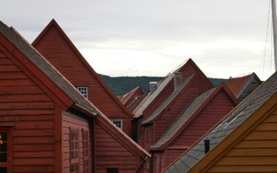 a row of red wooden houses with mountains in the background